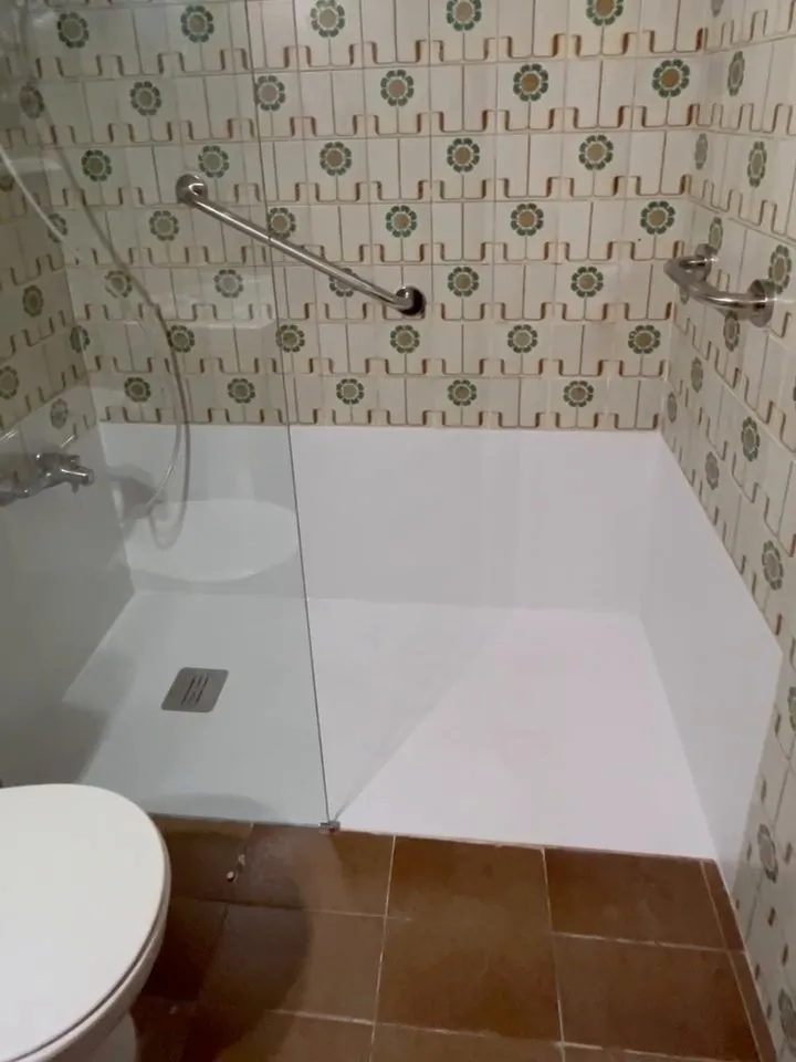 Ducha de un baño de Salt con plato blanco y mampara fija de vidrio en el lugar de la antigua bañera, bajo el azulejo antiguo de flores